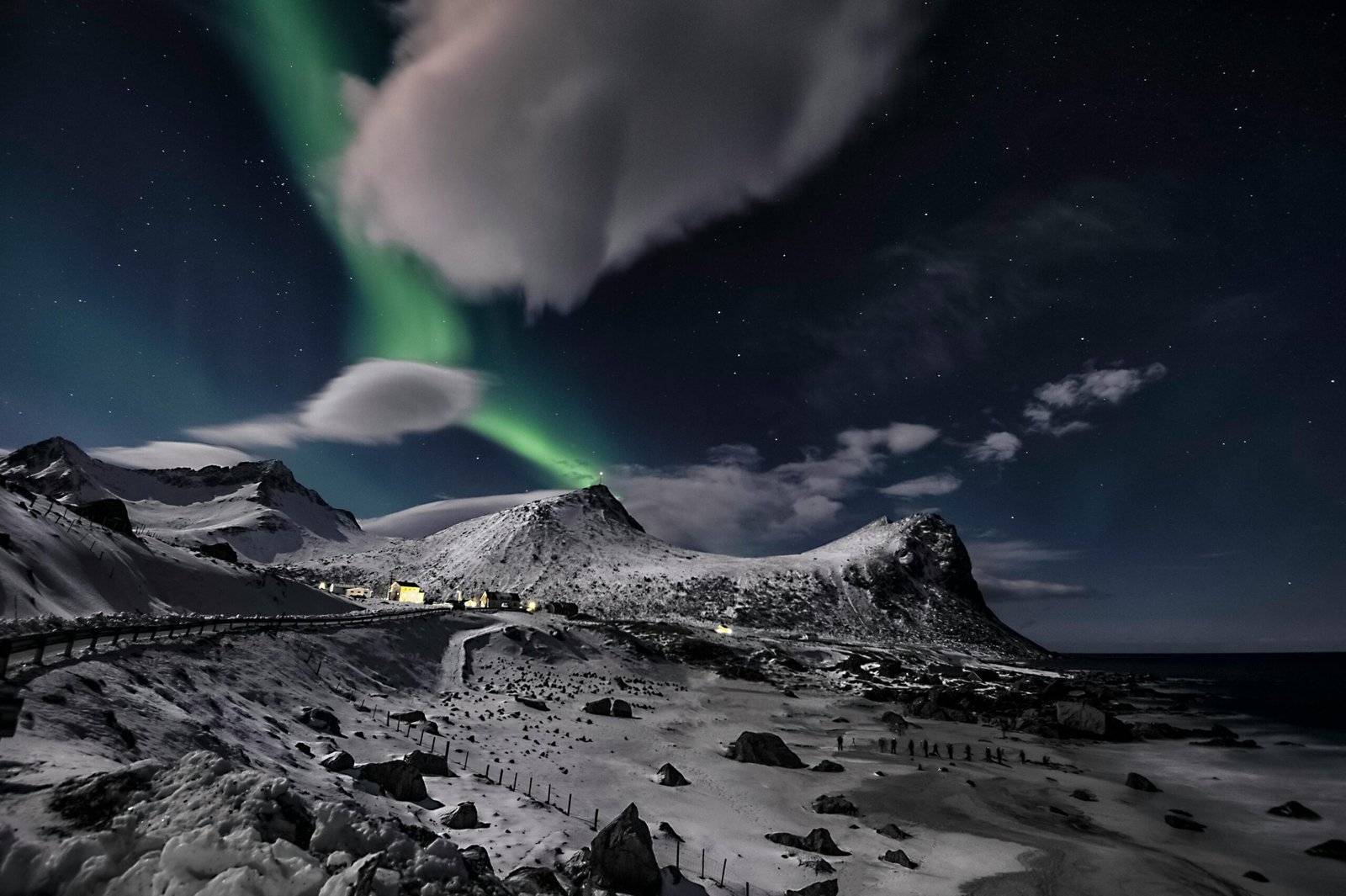 Majestic view of the aurora borealis illuminating a snowy coastal scene in Norway.